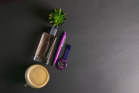 Women's parfums together with coffee with milk and green flower, next to there are purple watches and a pen top views with clear spaceの写真素材