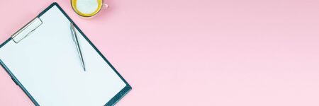 Tablet with a white sheet on which there is a silver pen and next to there is a glass with a coffe with milk.の写真素材