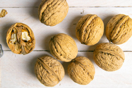 Closeup of walnuts scattered on a white wooden table.