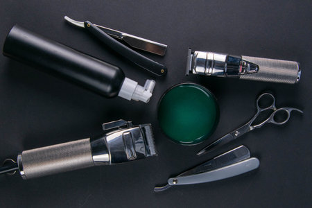 Scissors, hair clipper, combs, dangerous razor, gel for haircuts on black background. Hairdressing...