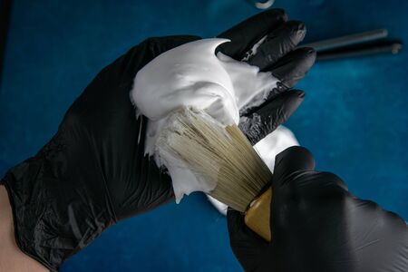 Hand holds brush for applying foam to the beard, foam and dangerous razor on blue background. Hairdressing concept.の写真素材