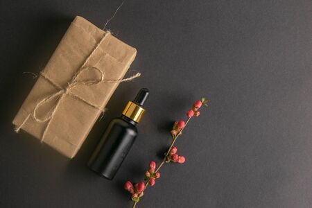 Banner with Wrapped in Eco craft holidays present gift boxes flower and black bottle with hand oil on black table top view. Flat lay styling. Copy space.の写真素材