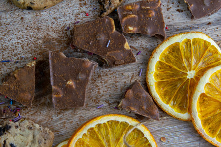 Dried oranges, chocolate slices, chocolate biscuits and cinnamon on a wooden table.の写真素材
