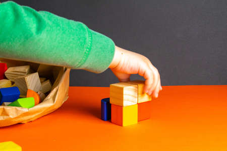 A child plays with wood cubes on an orange background.の写真素材