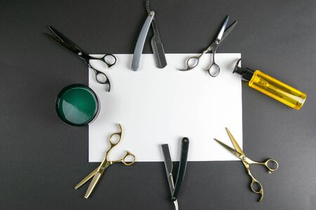 Scissors, hair clipper, combs, dangerous razor, gel for haircuts on a white sheet on black background. Hairdressing concept.の写真素材