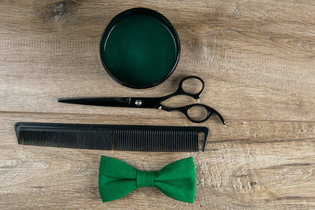 Green male butterfly, shaving gel, scissors and dangerous razor stand on a wodden background.