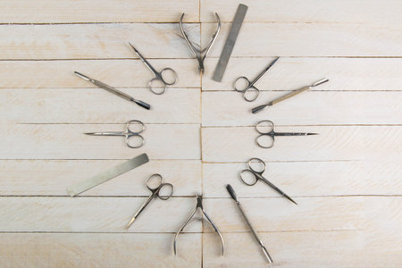 A set of cosmetic tools for manicure and pedicure on a white wooden background. Gel polishes laid...