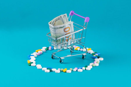 Shopping cart with tablet blisters and dollar banknote. Spending money on pills and expensiveness of...