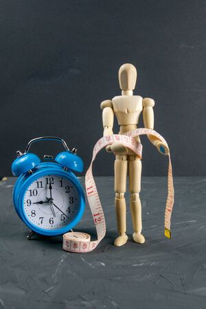Wood Figure Mannequin with measuring tape and blue clock, dieting Concept. Close-upの写真素材