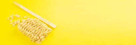 Instant noodles with wood sticks. Asian fast food on a yellow background close-up. Top views.の写真素材