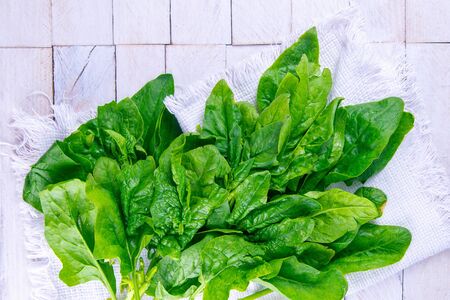 Freshly harvested spinach on a white towel, stand on white wooden table. Top views.の写真素材