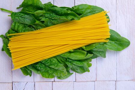 Creative layout made of spinach and noodles on white wooden background. Flat lay. Food concept. Macro concept.の写真素材