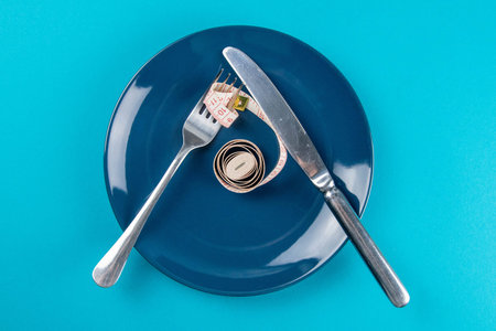 Measuring tape on a fork and knife - dieting concept image. Top views, close-up