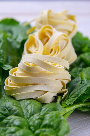Spinach and pasta tagliatelle on the white wooden background, photo studio. Top views, close-up.の写真素材