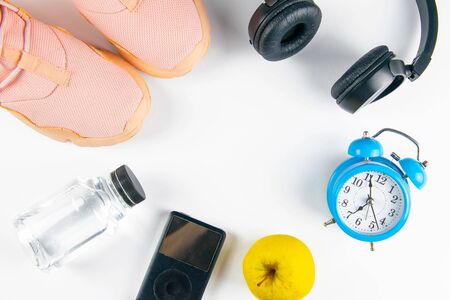 The diet plan. Pinc sneakers, headphones, bottles with water, clock and apples with measuring tape on a white background. Slimming and detox concept.の写真素材