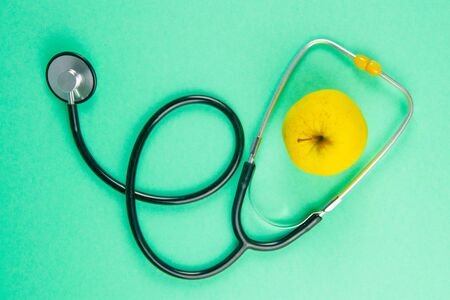 Fresh apples and stethoscope on light green background. Top views.の写真素材