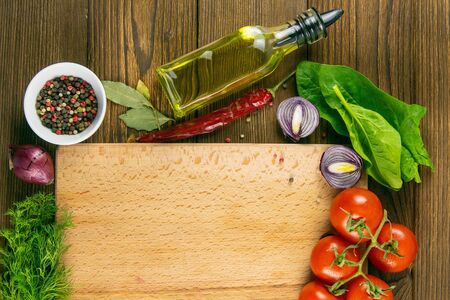 Wooden board with clear space. Around tomato and dill, olive oil, spice, peper, avocado, green onion, spinac and garlic. Top views.の写真素材