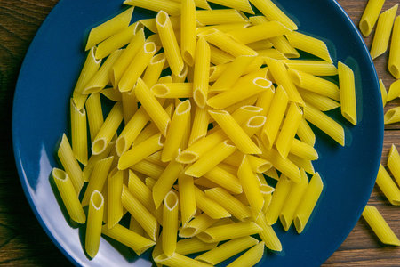 Pene Lisce pasta in blue plate on dark wooden background. Top views.