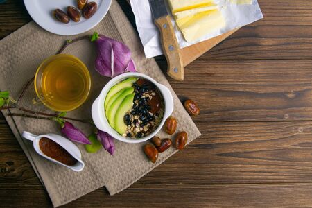 Healthy breakfast with oatmeal with bluberrys and avocado, next to it are yogurt, dates and apricot jam on wooden board. Top views with clear space.の写真素材