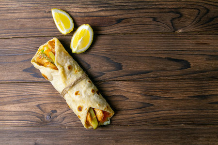 Doner wrap kebab. Shawarma with meat, onions, salad lies on a dark old wooden table. Top views with...