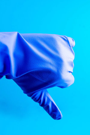 Doctor shows a gesture of dislike with his hand, wearing blue medical glove, emotion of negativity.