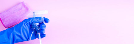 Female hand in blue rubber gHands in rubber protective gloves holding white spray bottle and rag....