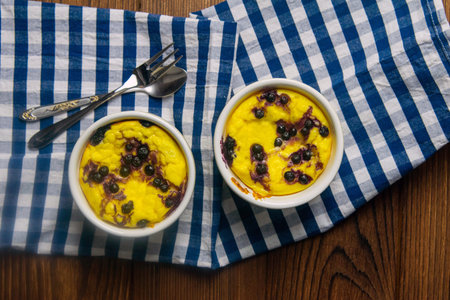Cottage cheese casserole with chocolate and blueberries in a white plate on a wooden table. Top...