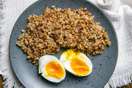 Buckwheat with boiled egg on white napkin on a rustic wooden table. Top views, close-up.の写真素材