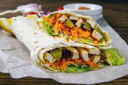Homemade shawarma, burrito, chicken roll with vegetables and sauce. Front view ingredients.の写真素材