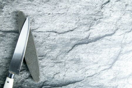 Knife and sharpening stone on grey marble background. Top views with clear space.の写真素材