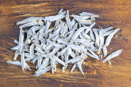 Dried salted anchovies on wooden background. Snack Fish to beer. Close up.の写真素材