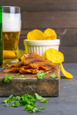 Dried perch with beer, lemon and potato chips on dark wooden board. Snack on fish with beer. Front views, close-up.の写真素材