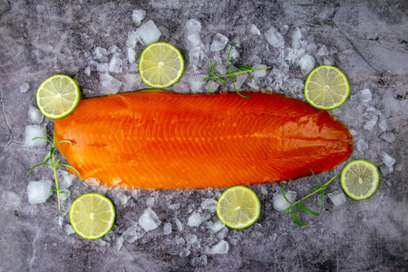Fresh raw salmon fish steak with spices on ice over dark stone