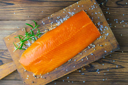 Raw salmon fillet with saltand rosemary on a old wooden Board. Top views, close-upの写真素材
