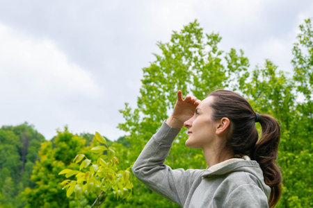 Beautiful girl looks into the cloudy sky against the backdrop of mountains