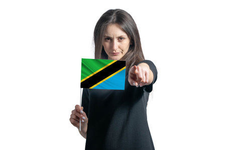 Happy young white woman holding flag of Tanzania and points forward in front of him isolated on a white background.の写真素材