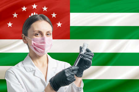 Girl doctor prepares vaccination against the background of the Abkhazia flag. Vaccination concept Abkhazia.の写真素材