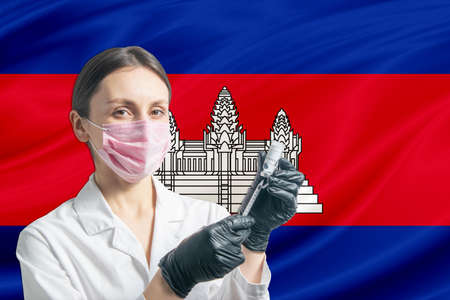Girl doctor prepares vaccination against the background of the Cambodia flag. Vaccination concept Cambodia.の写真素材