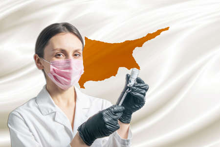 Girl doctor prepares vaccination against the background of the Cyprus flag. Vaccination concept Cyprus.の写真素材