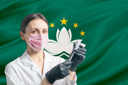 Girl doctor prepares vaccination against the background of the Macau flag. Vaccination concept Macau.の写真素材