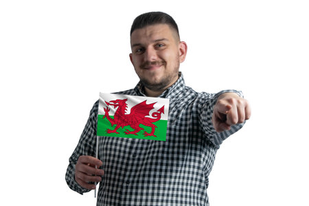 White guy holding a flag of Wales and points forward in front of him isolated on a white background.の写真素材