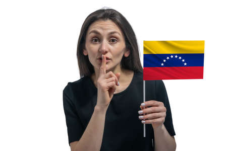 Happy young white woman holding flag of Venezuela and holds a finger to her lips isolated on a white background.の写真素材