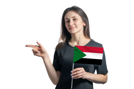 Happy young white woman holding flag Sudan and points to the left isolated on a white background.の写真素材