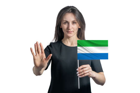Happy young white woman holding flag of Sierra Leone and with a serious face shows a hand stop sign isolated on a white background.の写真素材