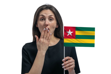 Happy young white woman holding flag of Togo and covers her mouth with her hand isolated on a white background.の写真素材