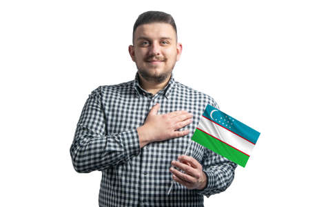 White guy holding a flag of Uzbekistan and holds his hand on his heart isolated on a white background With love to Uzbekistan.の写真素材