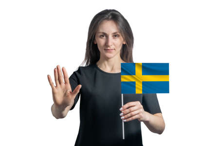 Happy young white woman holding flag of Sweden and with a serious face shows a hand stop sign isolated on a white background.の写真素材