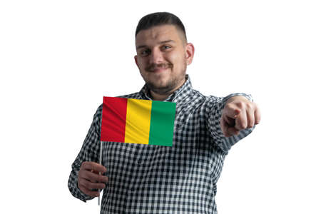 White guy holding a flag of Guinea and points forward in front of him isolated on a white background.の写真素材