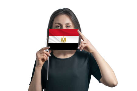 Happy young white woman holding flag Egypt flag and covers her face with it isolated on a white background.の写真素材