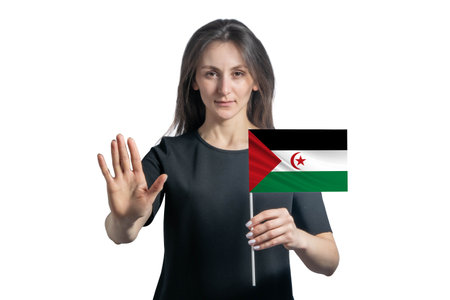 Happy young white woman holding flag of Western Sahara and with a serious face shows a hand stop sign isolated on a white background.の写真素材